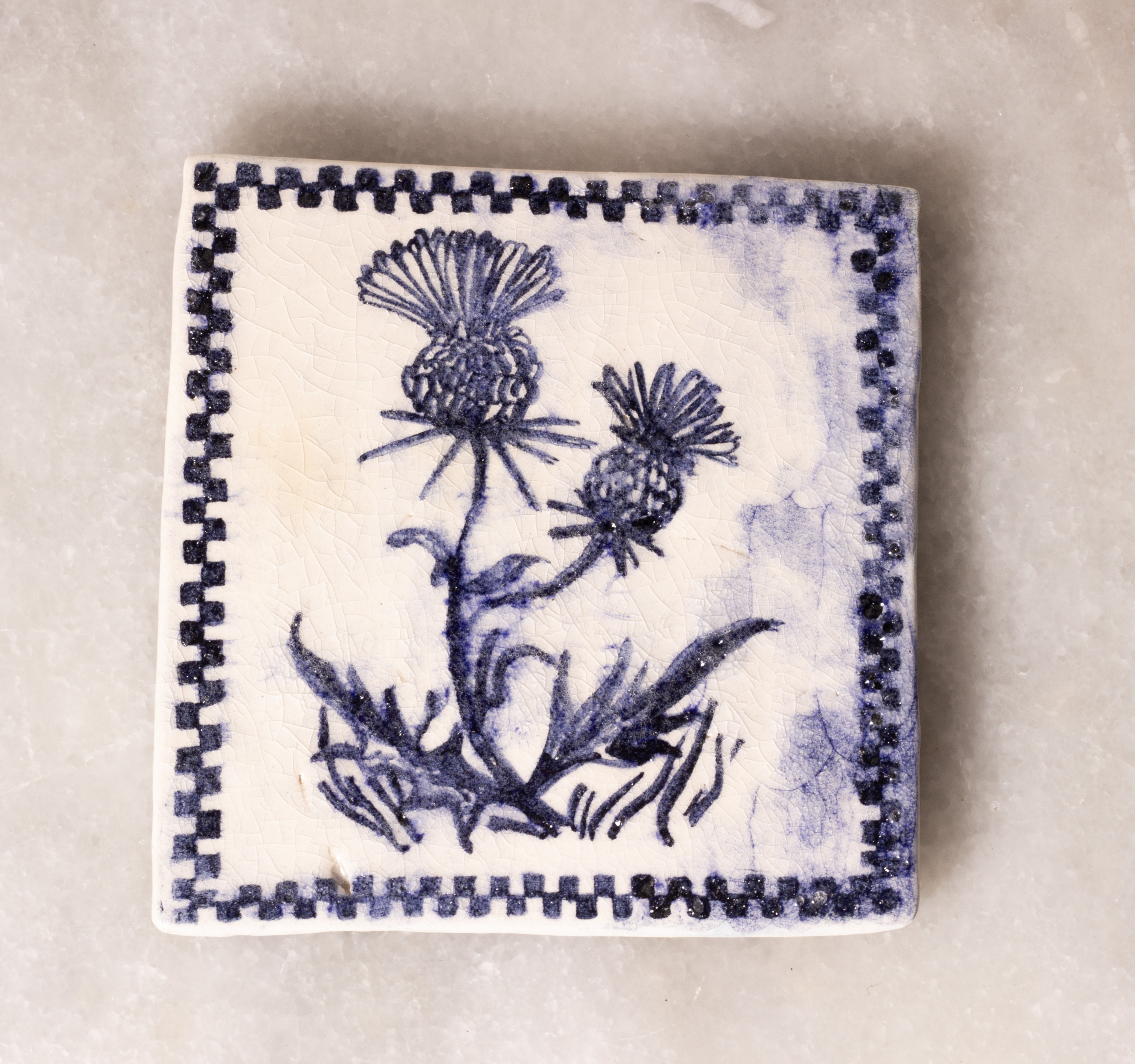 carreau de faïence blanc peint en bleu à l'oxyde de cobalt. Il représente des chardons