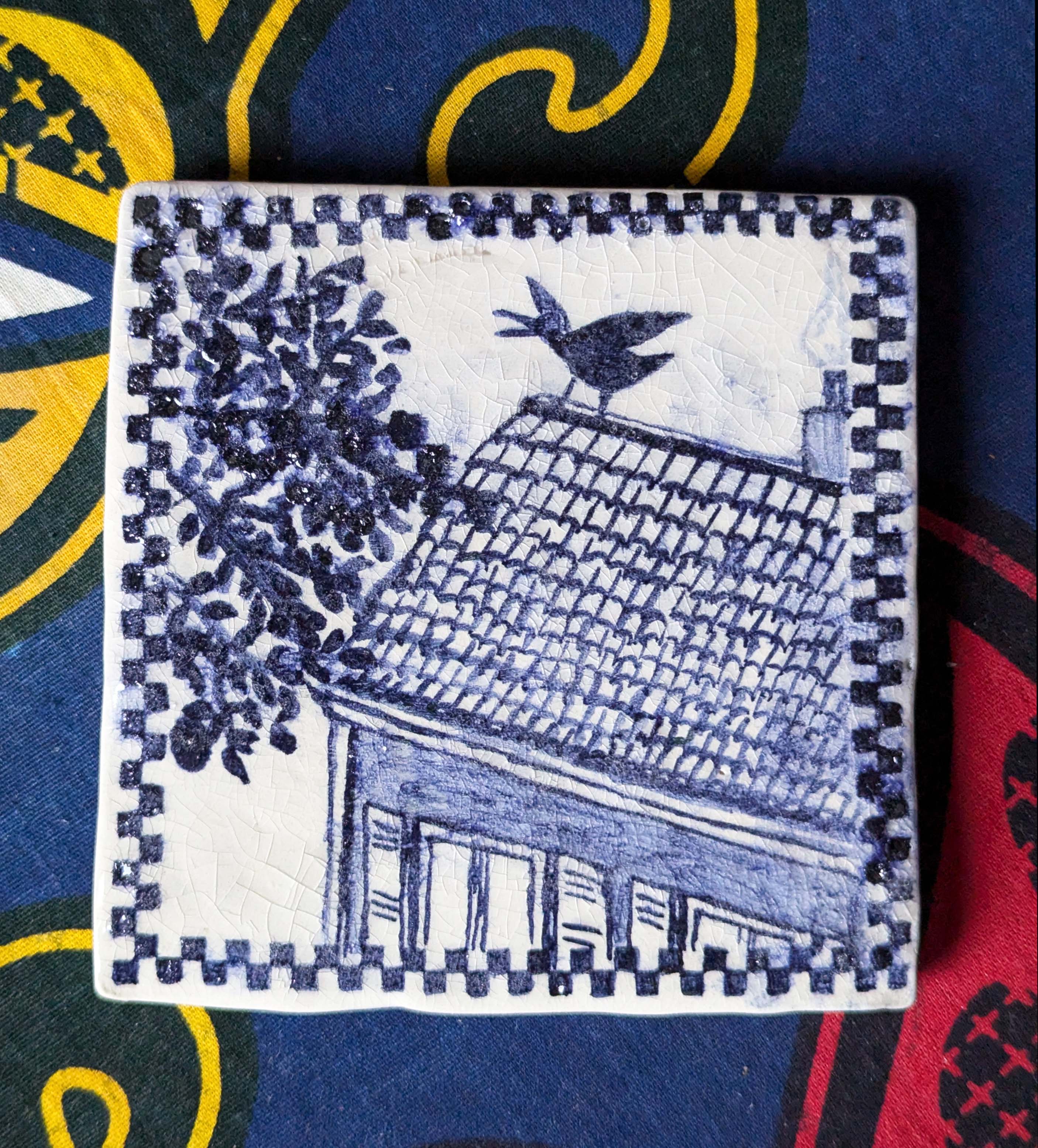 carreau de faïence blanc peint en bleu à l'oxyde de cobalt. Il représente une corneille sur un toit en tuiles, avec des branchages à gauche