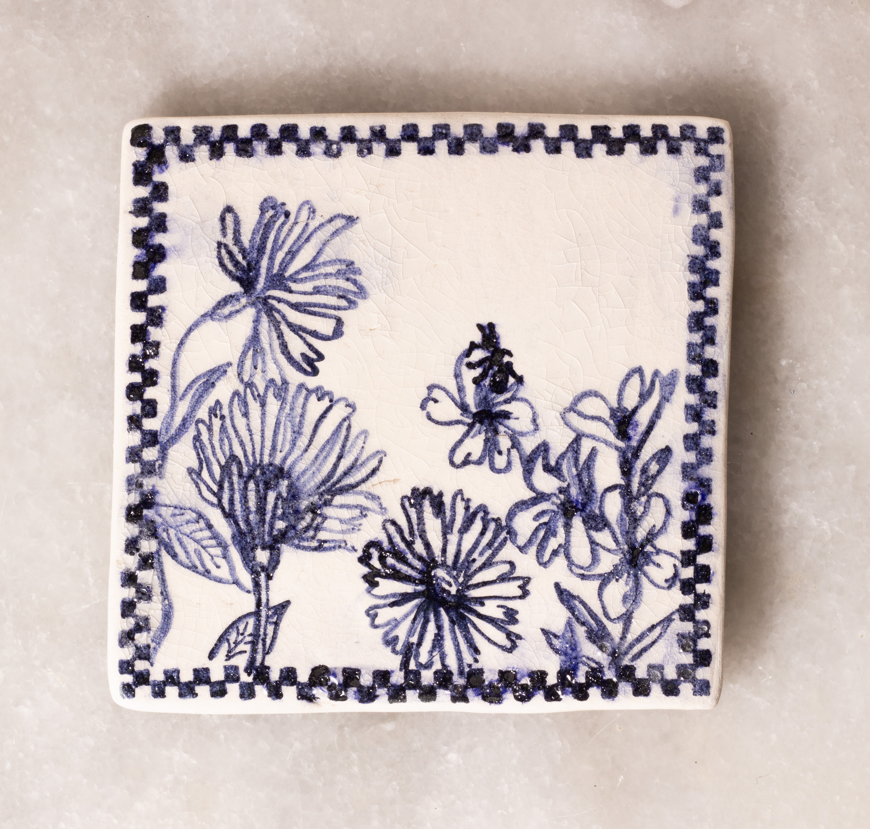 carreau de faïence blanc peint en bleu à l'oxyde de cobalt. Il représente des fleurs sauvages, sur une desquelles est posée une fourmi