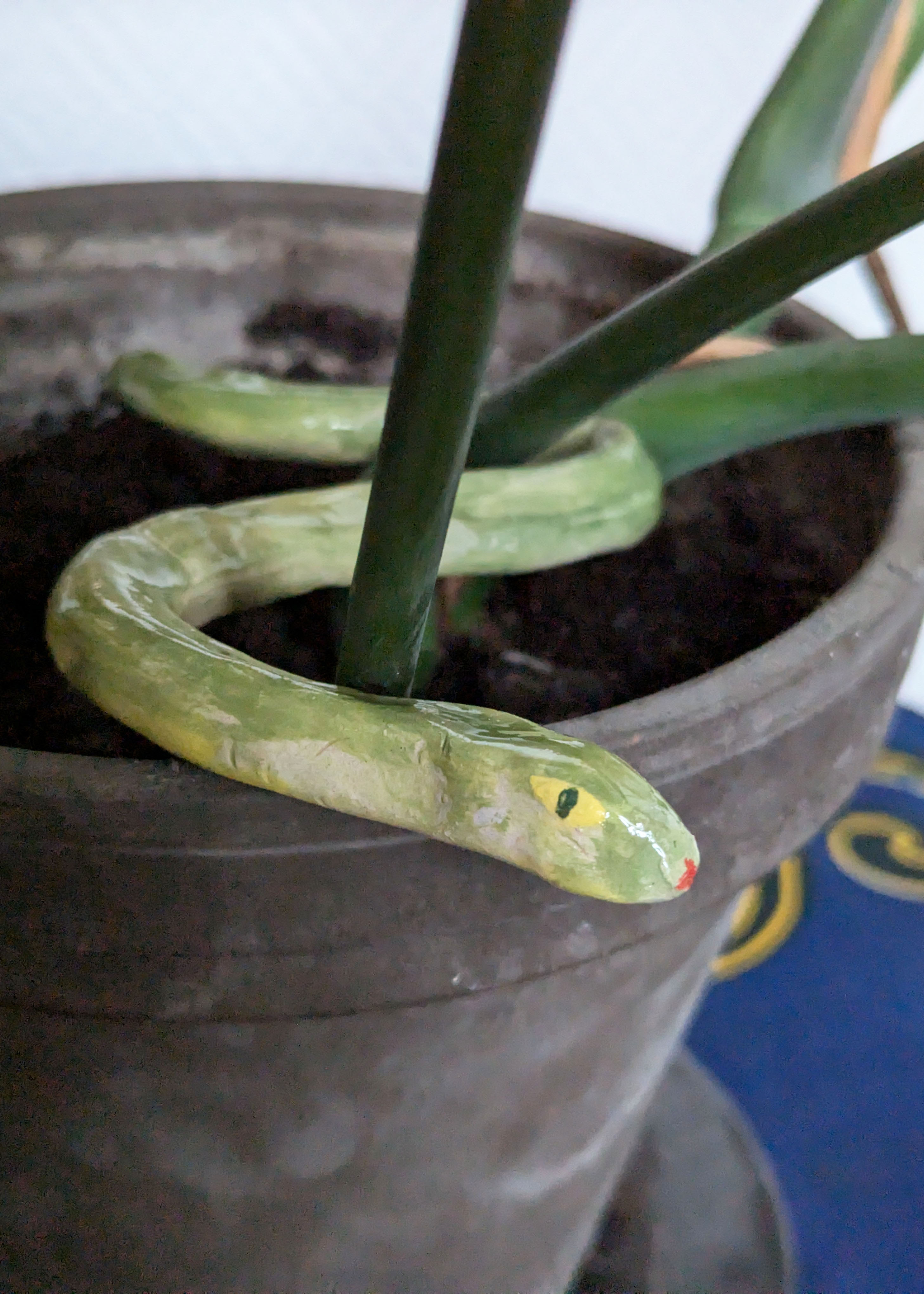 serpent en grès vert et jaune dans un philodendron