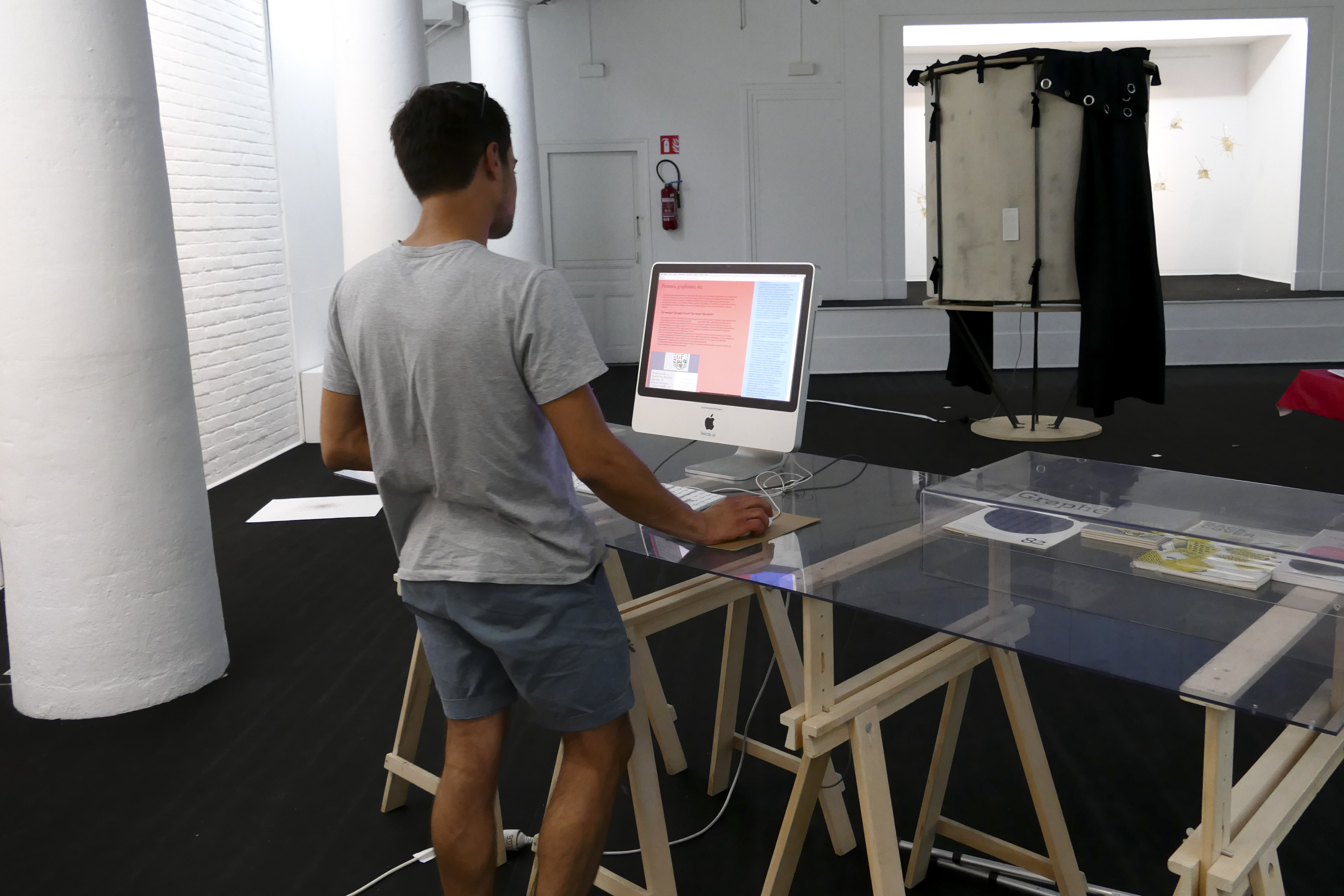 photo de l'exposition Chassé-croisé où un jeune homme de dos consulte le site Femmes, graphisme, etc.